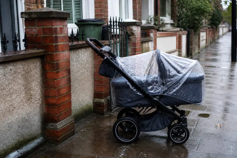 A lie-flat pram on a wet UK pavement
